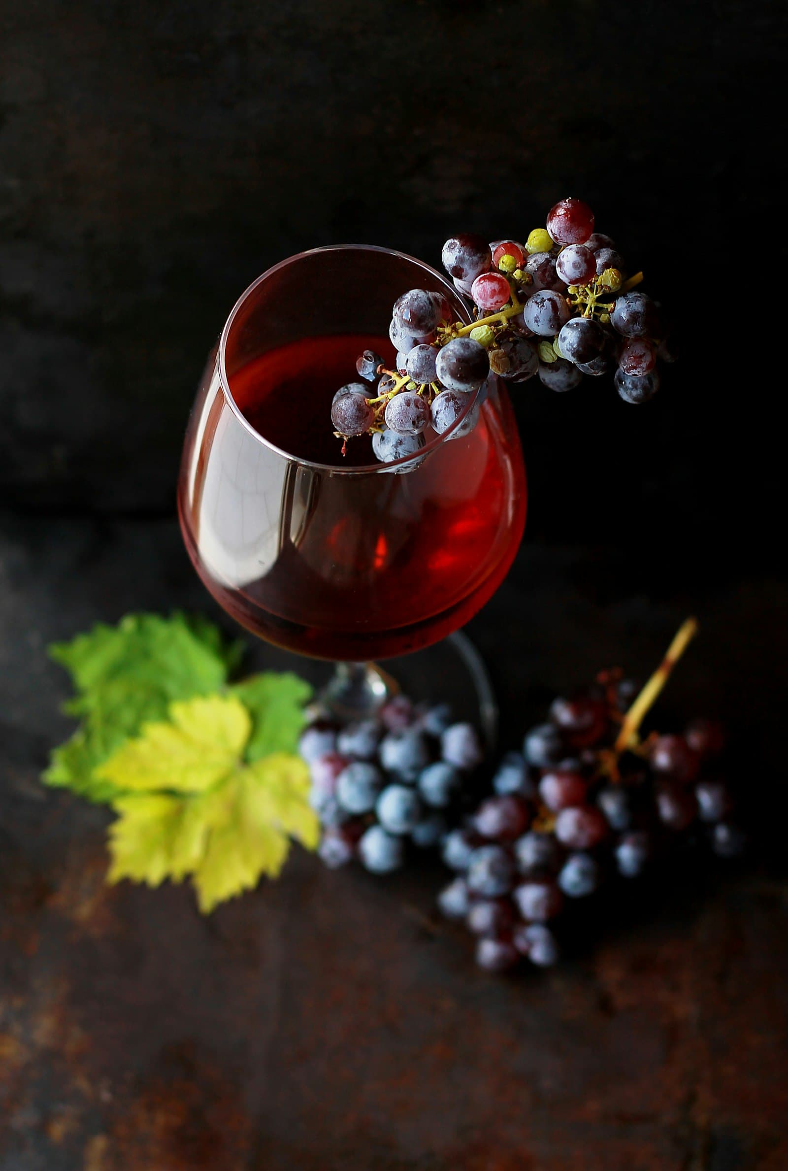 Verre de vin rouge et grappe de raisin sur un fond sombre, lumière intime.